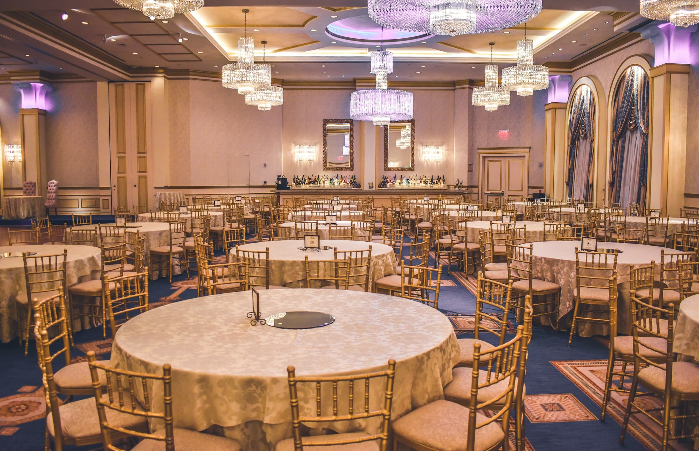 Elegant event venue set for a celebration, with round tables and soft ambient lighting.