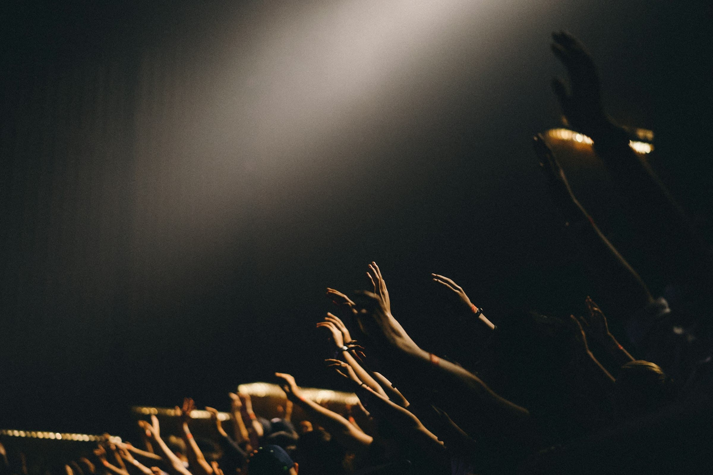 Raised hands and stage lighting during a live event production.