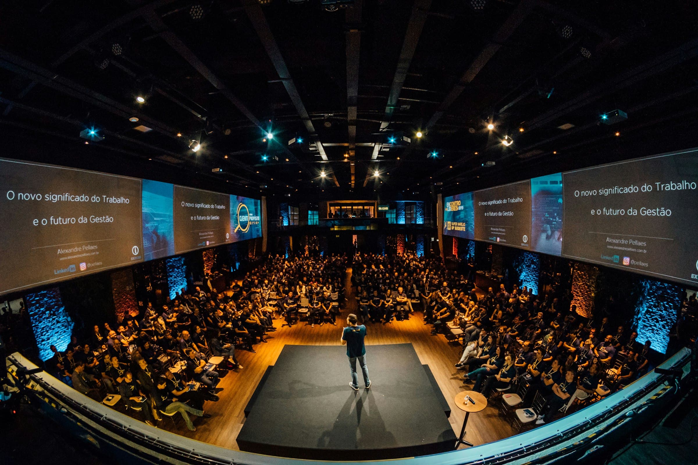 Speaker addressing a large audience on stage at a leadership conference.
